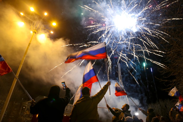 People in Donetsk wave Russian national flags celebrating Moscow's recognition of the breakaway region of Ukraine