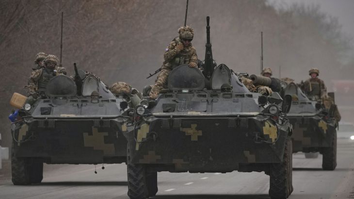 Ukrainian servicemen sit atop armored personnel carriers driving on a road in the Donetsk region, eastern Ukraine