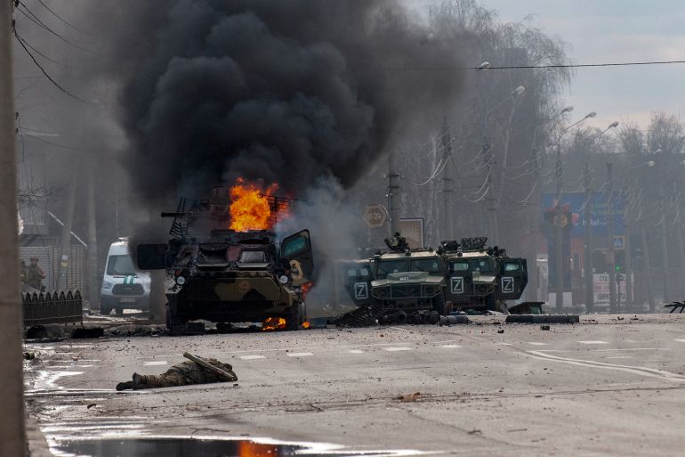 A Russian armored personnel carrier burns amid damaged and abandoned light utility vehicles after fighting in Kharkiv, Ukraine, Sunday, February 27, 2022. The city authorities said that Ukrainian forces engaged in fighting with Russian troops that entered the country's second-largest city on Sunday. [AP Photo/Marienko Andrew]