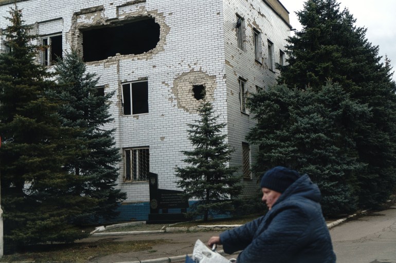 Someone cycles past a damaged building in Marinka