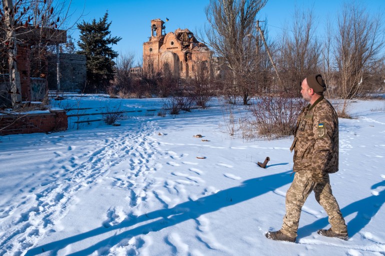A Ukrainian soldier walks near a church destroyed by the front line