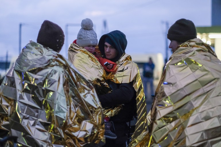 Paramedics wrap refugees from Ukraine with golden 'space blankets' to prevent hypothermia.