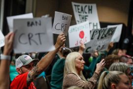 Parents hold banners that read "Ban CRT" at a school board meeting in Los Angeles