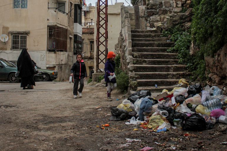 Children play in the street among rubbish.