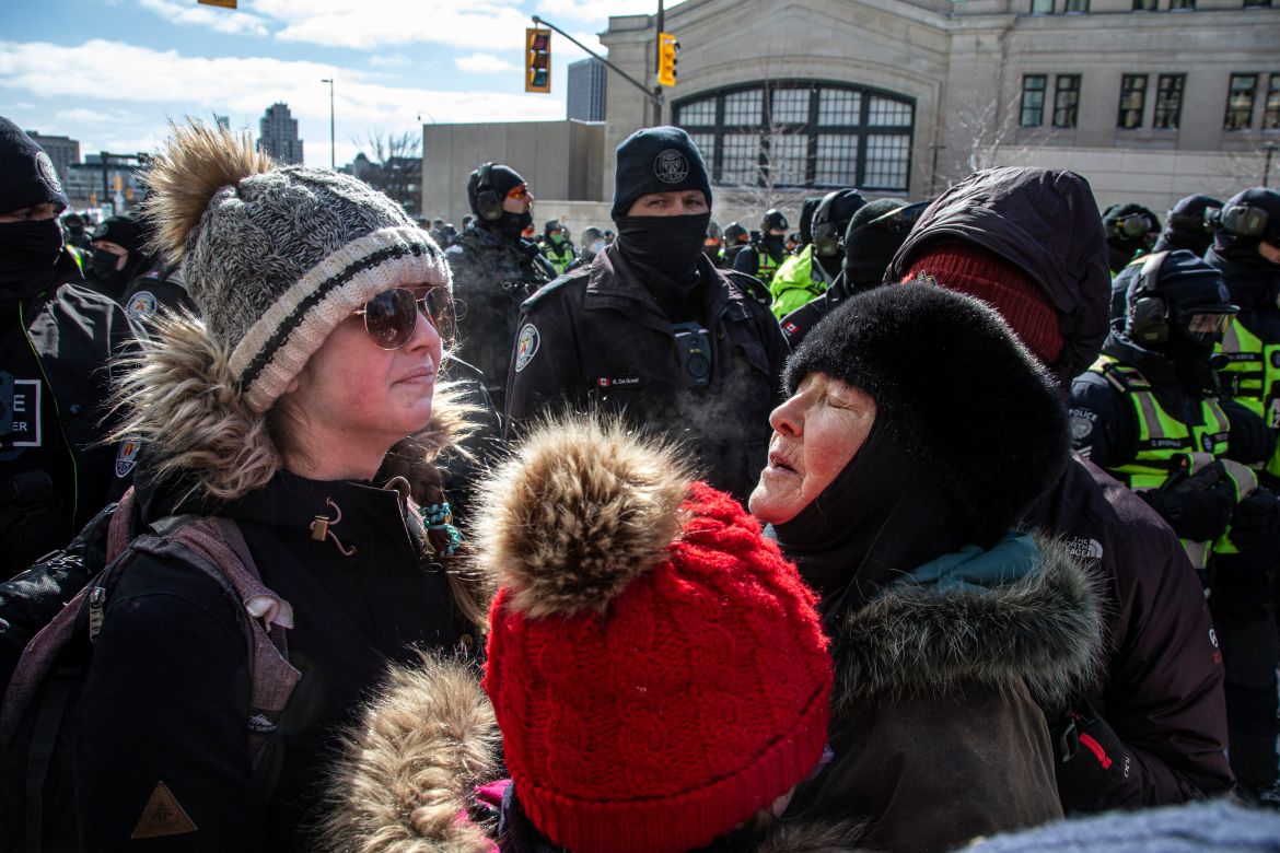 Protesters huddle together in front of a police line in Ottawa