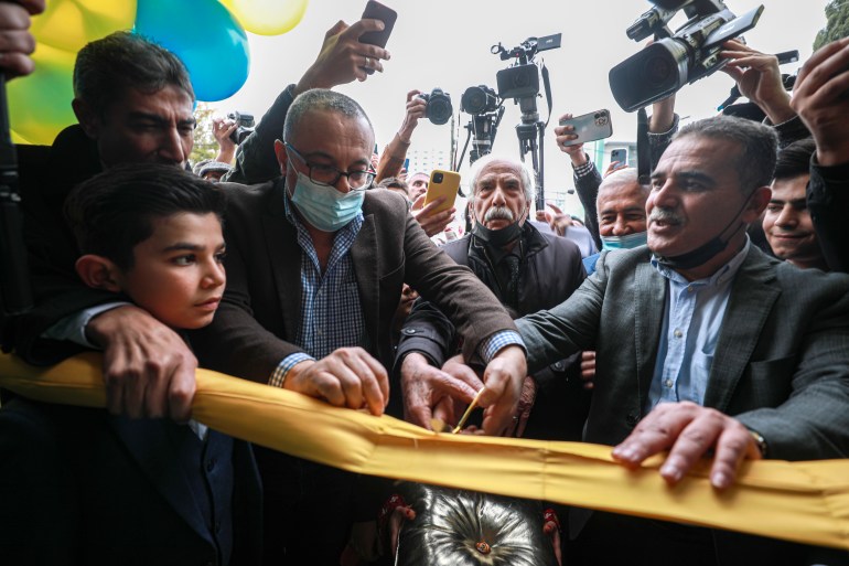 A man cuts a ribbon at the reopening of a store in Gaza