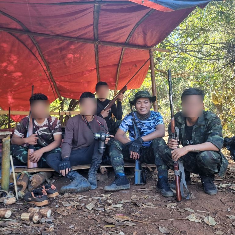 Khun Nan Nan seen with a group of fighters, with one of them holding a camera and the others are holding rifles.