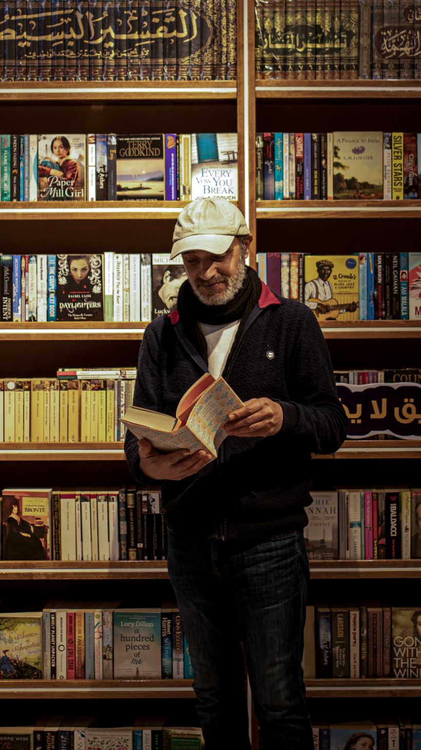 A man reads a book in front of a bookstore