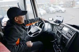 Truck driver Romando poses at the steering wheel