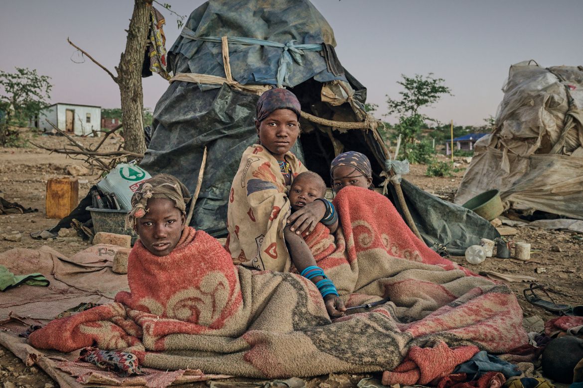 A photo of a woman and her family laying down on blankets outside a tent.