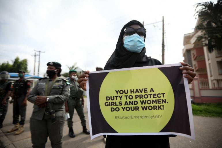 A protester wearing face mask, carries a banner outside the Nigerian Police Headquarters in Abuja, Nigeria, during a demonstration to raise awareness about sexual violence in Nigeria.