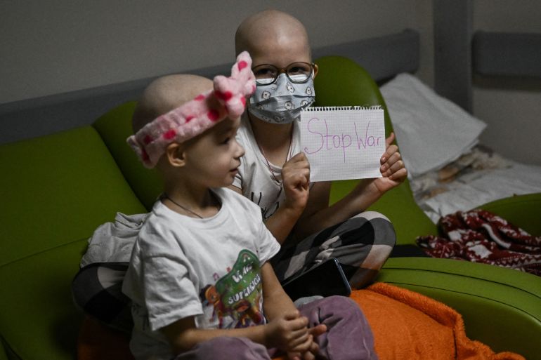 A child struggling with cancer holds a sign that says "Stop War" in the bomb shelter located in the basement of an oncology center in Kyiv on February 28, 2022