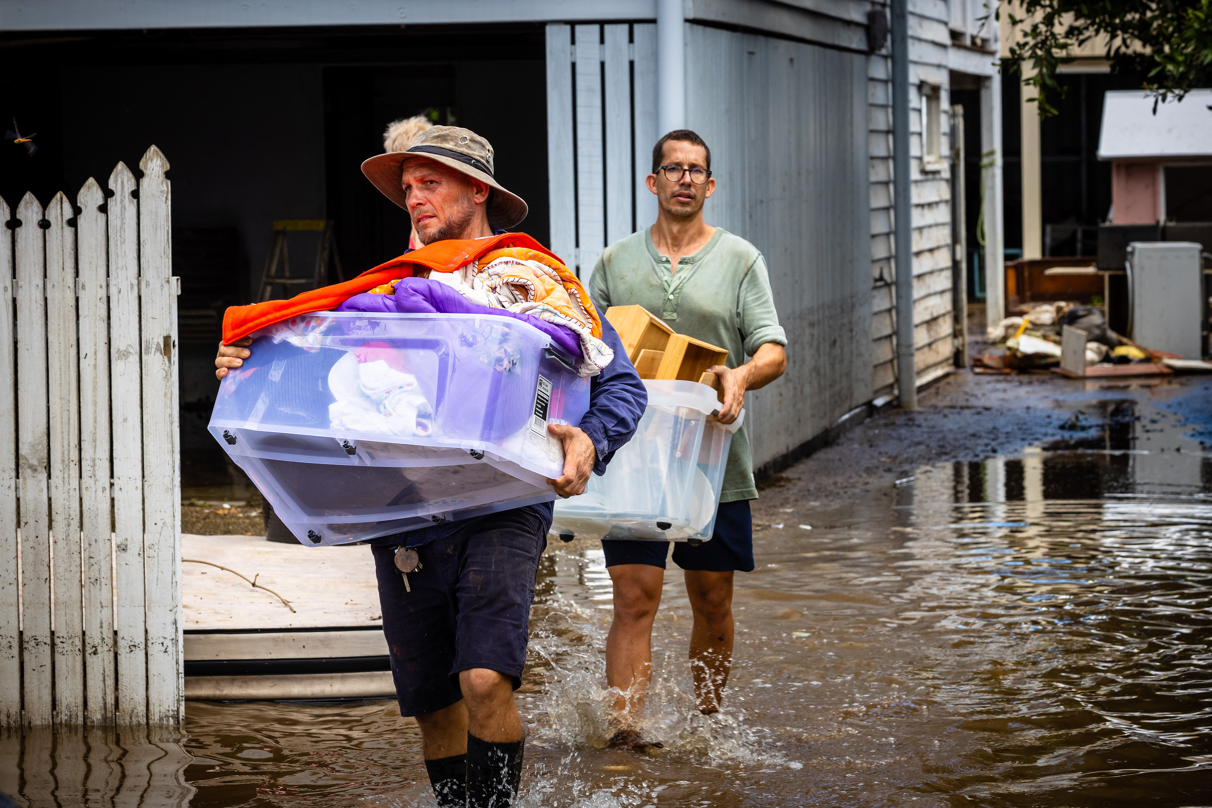 Residents carry belongings as they clean their homes in the flood-damaged suburb of Newmarket in Brisbane