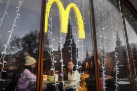 In this file photo taken on January 30, 2020, people look out of the window of a McDonald's restaurant as the towers of the Kremlin are reflected in Moscow.