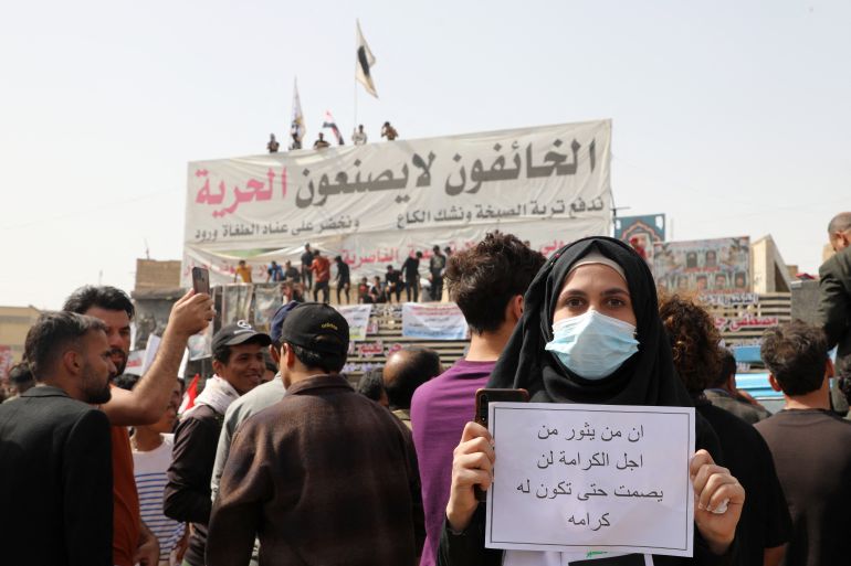 An Iraqi carries a placard which reads in Arabic "Then you revolt for pride, you won't stop until you achieve your goal" during a demonstration to denounce rising prices of basic food items, in al-Haboubi Square in the centre of Iraq's city of Nasiriyah in the southern Dhi Qar province on March 9, 2022.