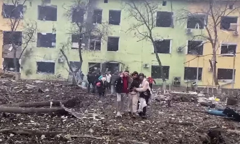 In this video grab from a handout footage taken and released by the the National Police of Ukraine on March 9, 2022, people are helped out of a damaged building of a children's hospital following a Russian air strike in the southeastern city of Mariupol.