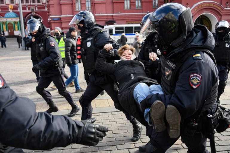 Police officers detain a woman during a protest against Russian military action in Ukraine.
