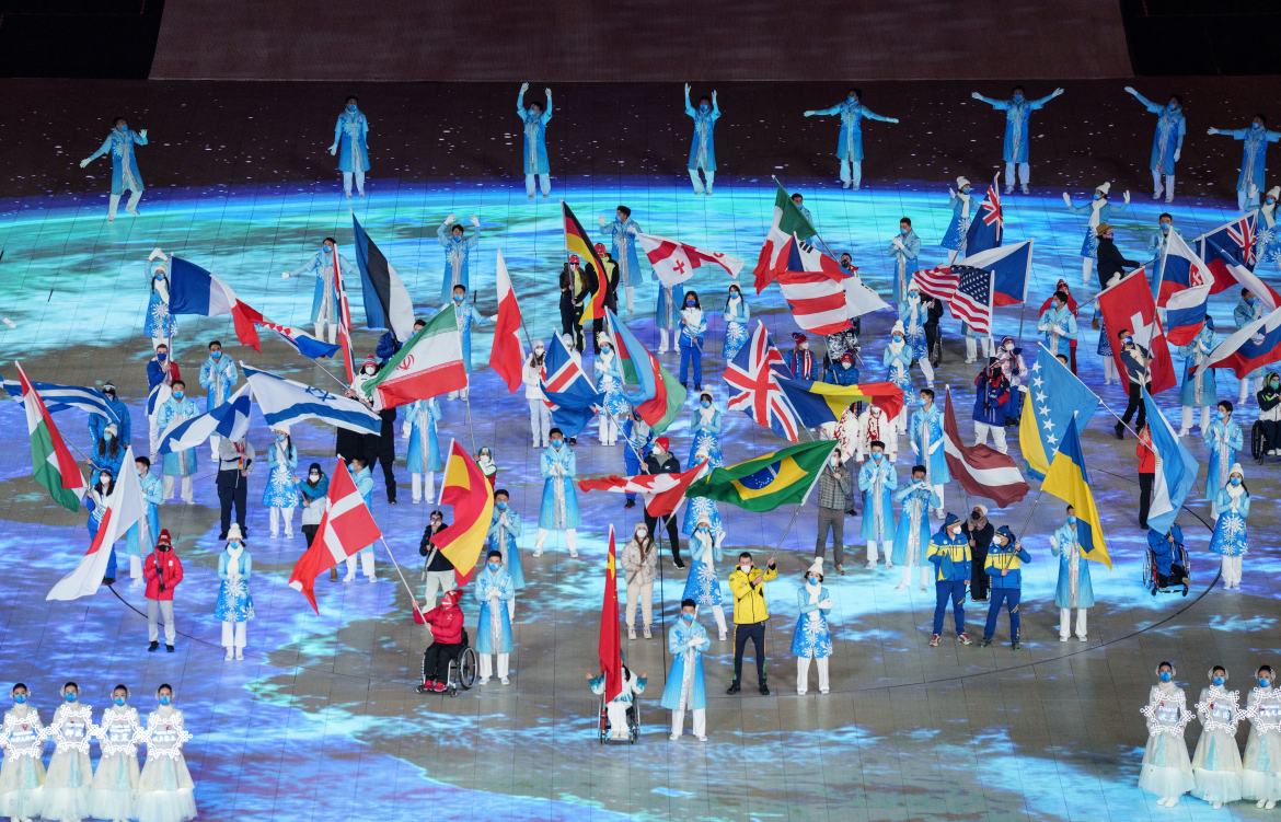 This handout photo taken and received from the OIS/IOC on March 13, 2022 shows flagbearers waving their national flags during the closing ceremony of the Beijing 2022 Winter Paralympic Games