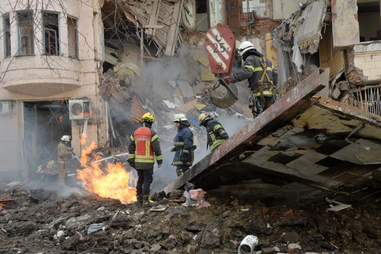 Firemen work to clear the rubble and extinguish a fire