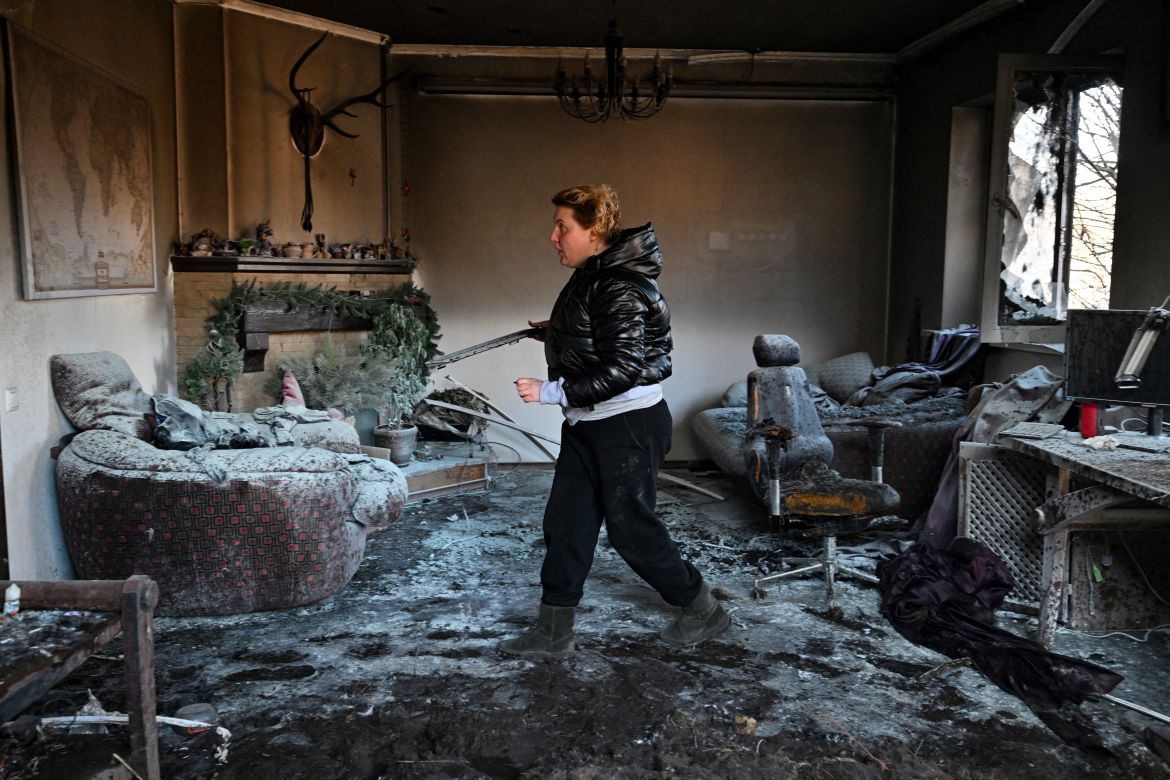 A woman inspects debris inside a private house damaged by shelling in the Osokorky
