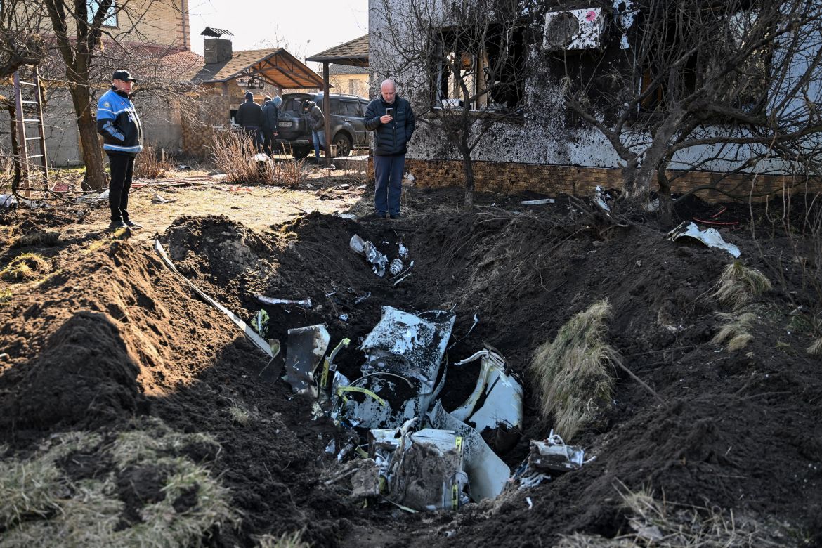A man takes pictures of the remains of a missile in the yard of a private house hit by shelling in the Osokorky district