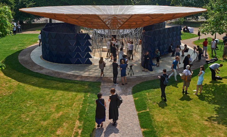 People mill around on the grass near the pavilion designed by Diebedo Francis Kere at London's Serpentine Gallery in 2017