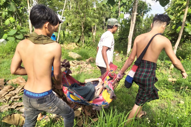 Three villagers carry a sick person on a n improvised stretcher into the forest after they were forced to flee in Myanmar's Kayah state