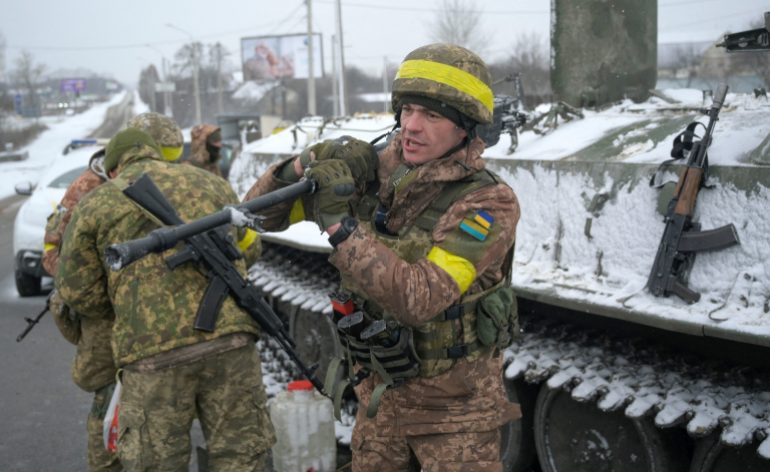 Ukrainian servicemen are seen standing guard on a road in Kharkiv