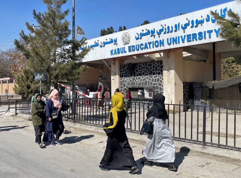 Women walk past a university in Kabul in 2022