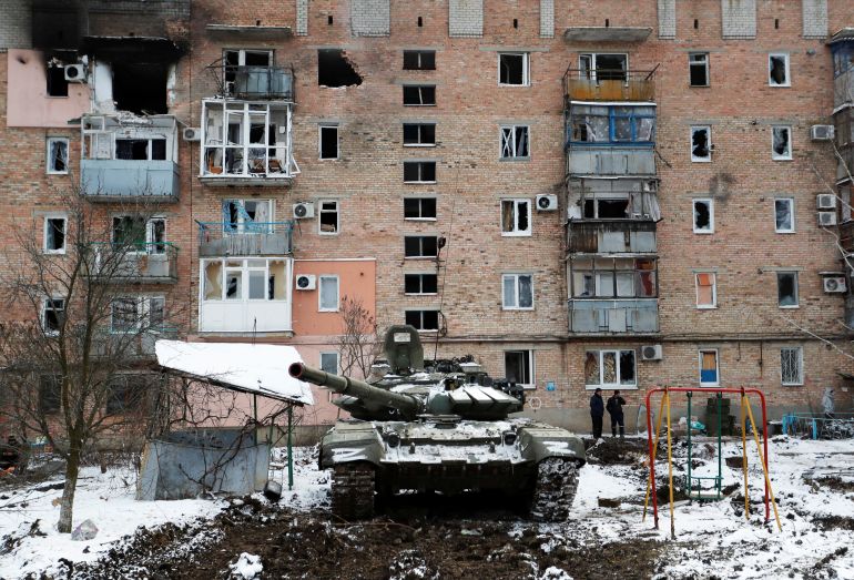 A tank with the letters "Z" painted on it is seen in front of a residential building which was damaged during Ukraine-Russia conflict in the separatist-controlled town of Volnovakha in the Donetsk region, Ukraine