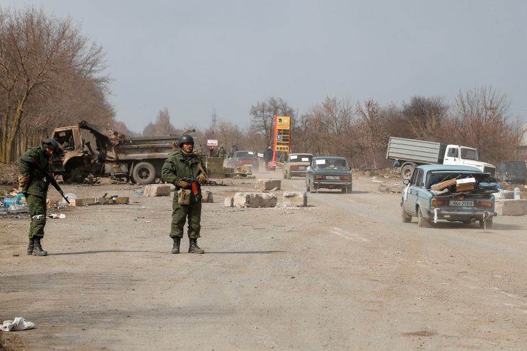 Service members of pro-Russian troops stand guard at a checkpoint
