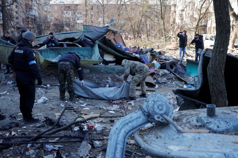 Rescue workers move the body of a person who was killed when a shell hit a residential building, as Russia's invasion of Ukraine continues, in Kyiv, Ukraine March 18, 2022