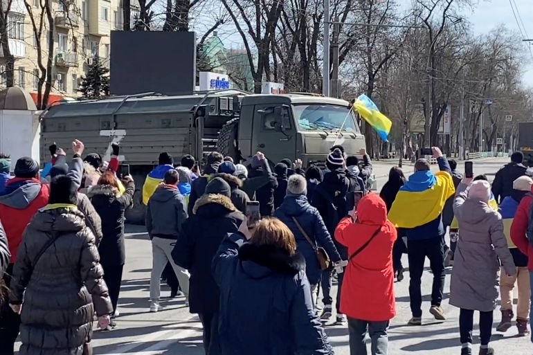 Demonstrators, some displaying Ukrainian flags, chant "go home" while walking towards retreating Russian military vehicles at a pro-Ukraine rally amid Russia's invasion, in Kherson, Ukraine March 20, 2022