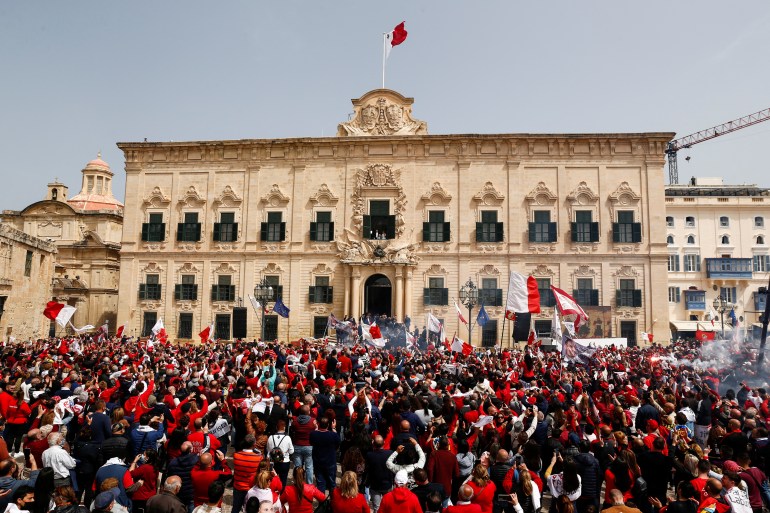Supporters gather outside the office of the prime minister as Malta's Prime Minister Robert Abela, his wife Lydia Abela and their daughter, Giorgia Mae, wave from a window at Auberge de Castille, after his swearing-in for another term