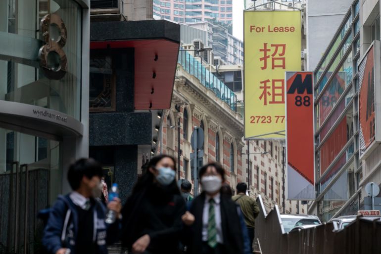Pedestrians walk past a "For lease" sign outside a commercial building in the Central district of Hong Kong, China