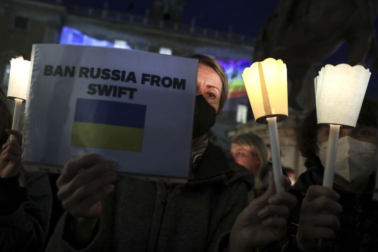 A demonstrator holds a sign reading "Ban Russia From Swift" during a candlelit march to show support for people of Ukraine in Italy