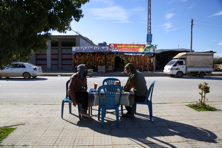 Two customers enjoy fruit cocktails at a table on the opposite side of the street from the juice shop.