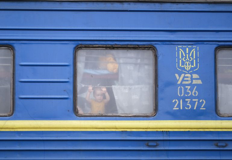 A photo of a window of train with a child looking through.
