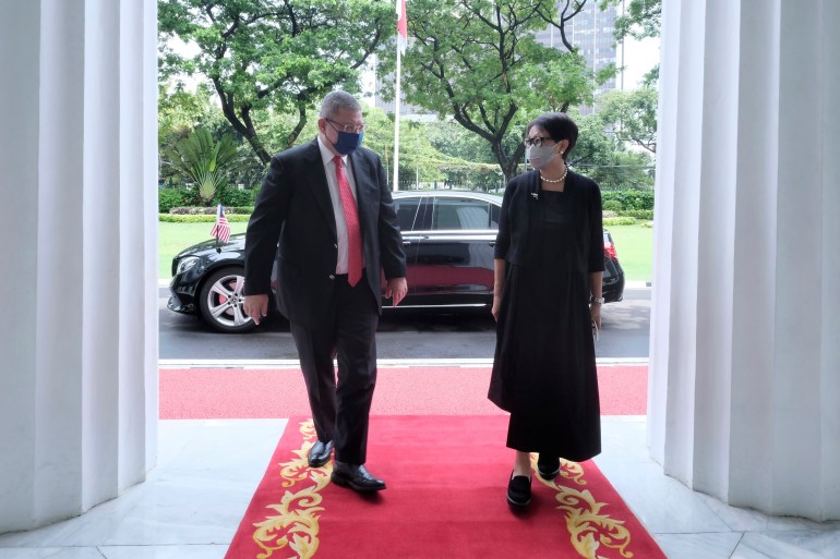 Malaysia's foreign minister Saifuddin Abdullah (on left in a suit) and Indonesia's foreign minister Retno Marsudi (right in black top and skirt) walk into a building during a meeting in Jakarta