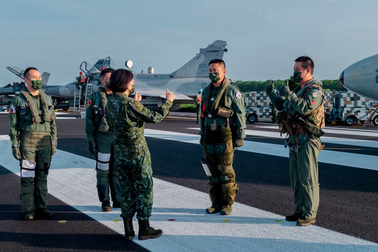 A photo of Taiwanese President Tsai Ing-wen, center, speaks with military personnel near aircraft parked on a highway in Jiadong, Taiwan.