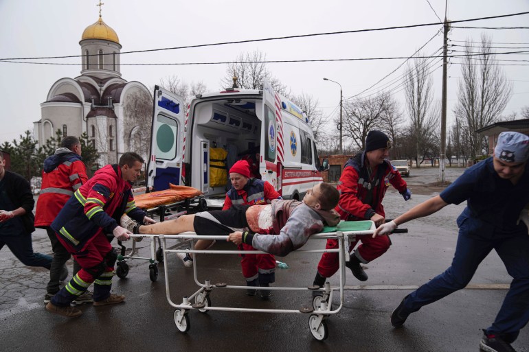 Ambulance paramedics move an injured man on a stretcher, wounded by shelling in a residential area, at a maternity hospital converted into a medical ward and used as a bomb shelter in Mariupol