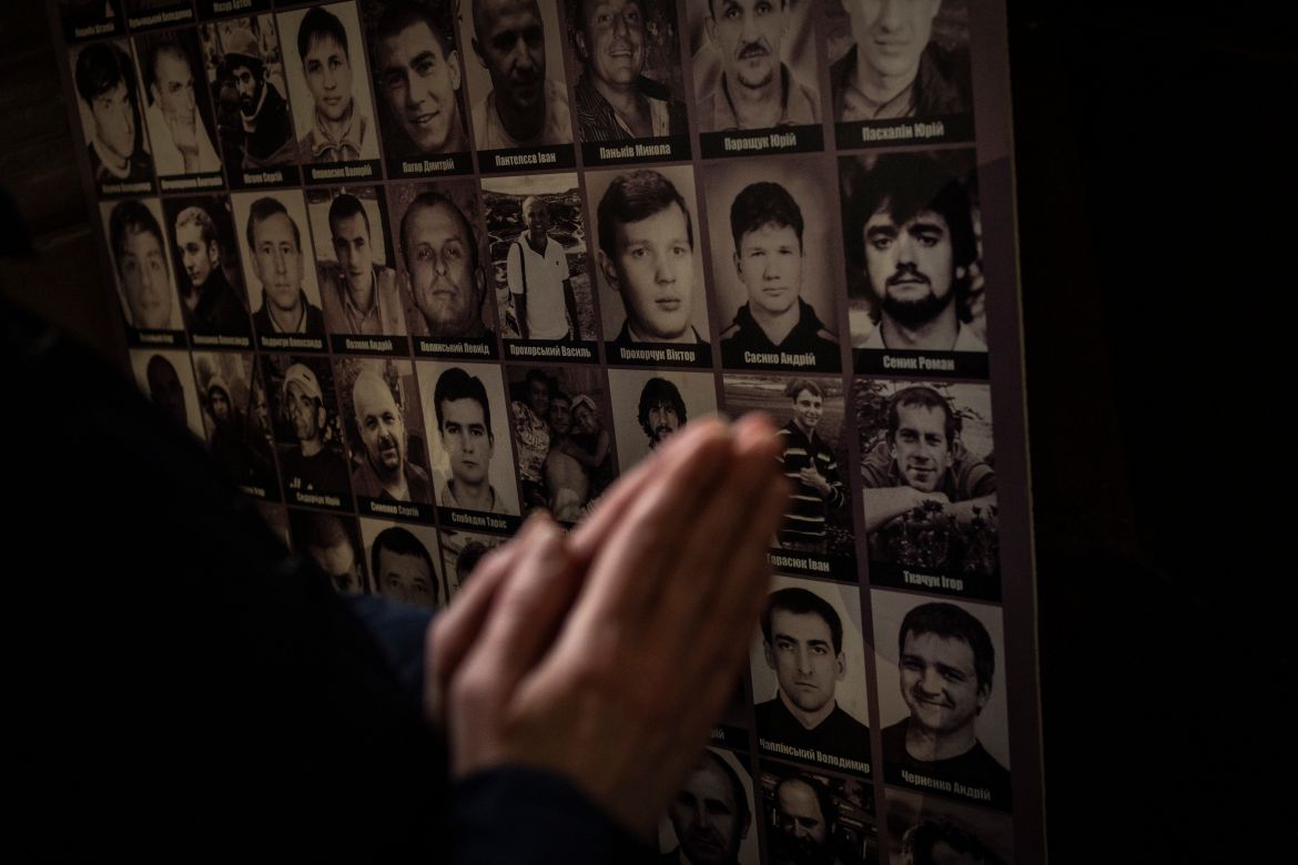 A Christian worshipper prays in front of pictures of fallen soldiers at the Saints Peter and Paul Garrison Church in Lviv