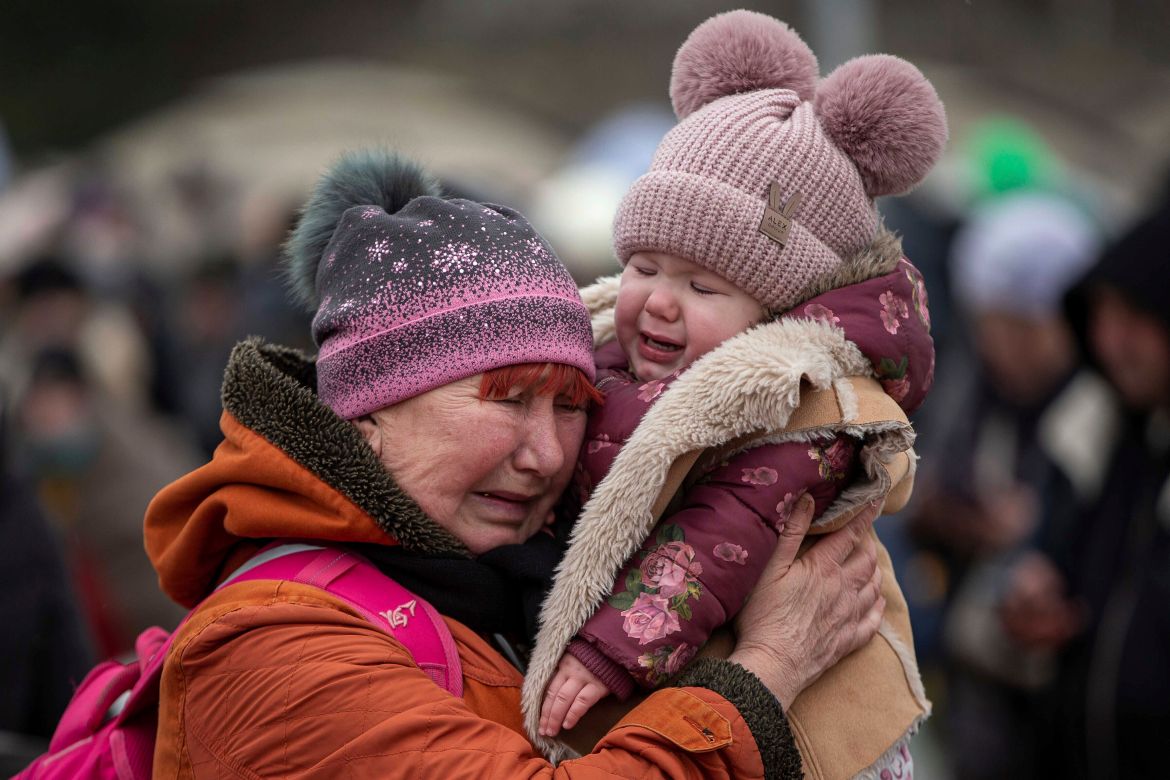 A woman holding a child cries after fleeing from Ukraine and arriving at the border crossing in Medyka