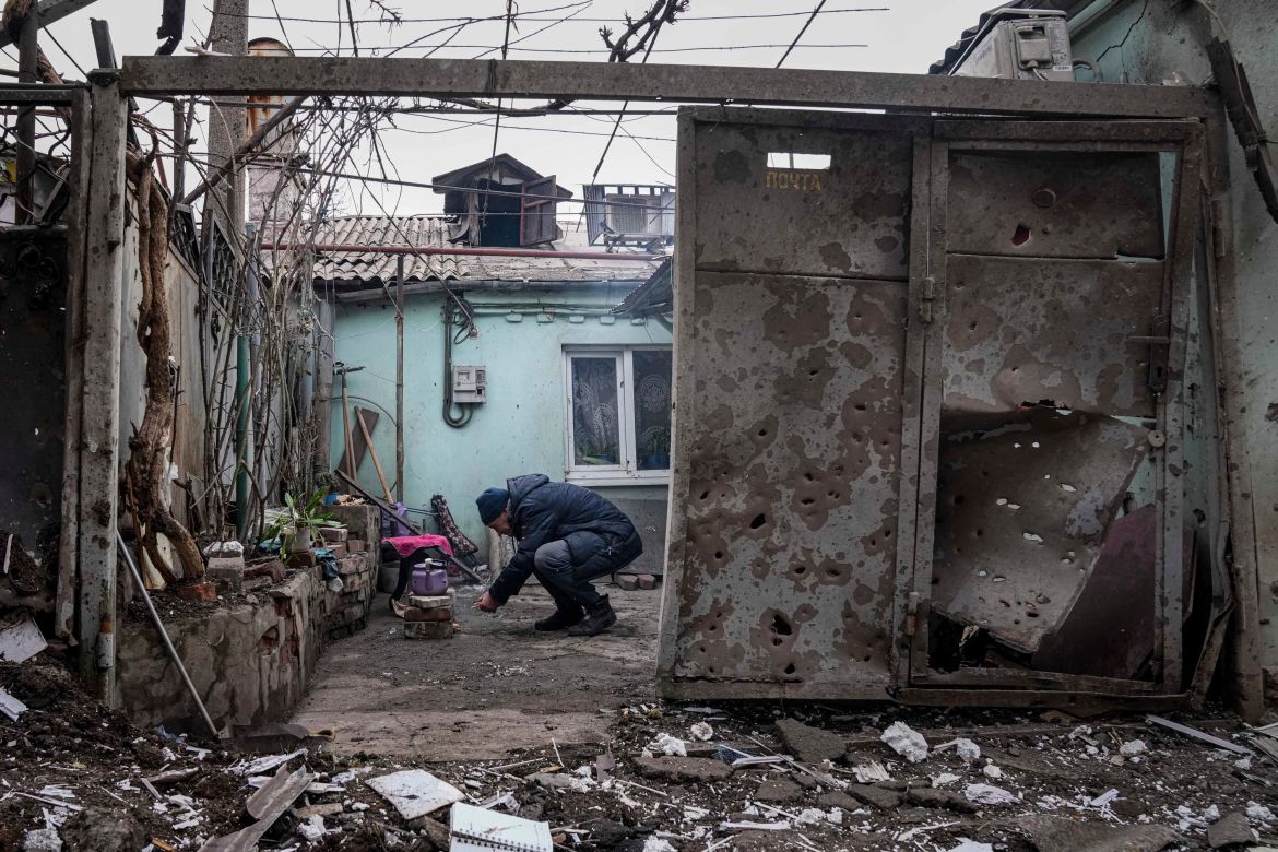A man lights a fire under the kettle in a yard of an apartment building hit by shelling in Mariupol