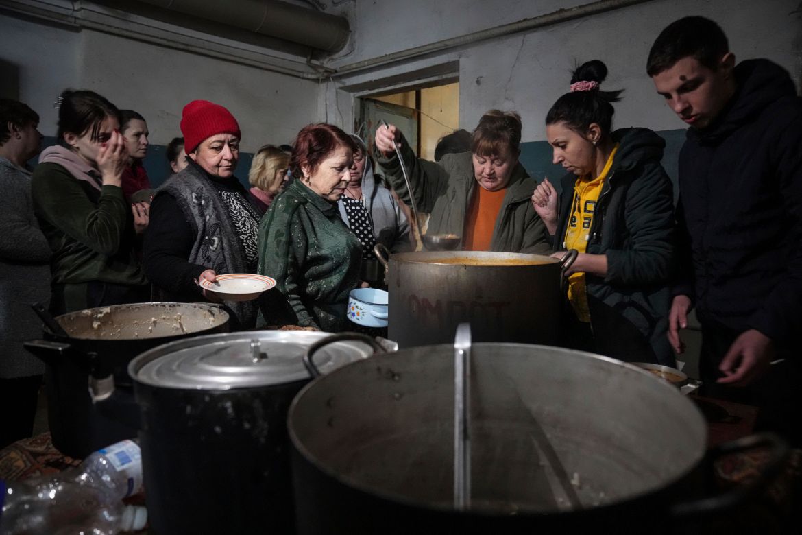 People queue to receive hot food in the improvised bomb shelter
