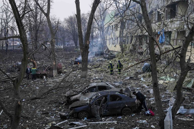 Ukrainian emergency employees work at the side of the damaged by shelling maternity hospital in Mariupol