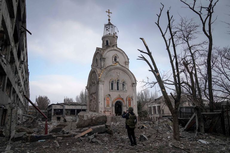 A Ukrainian serviceman takes a photograph of a damaged church
