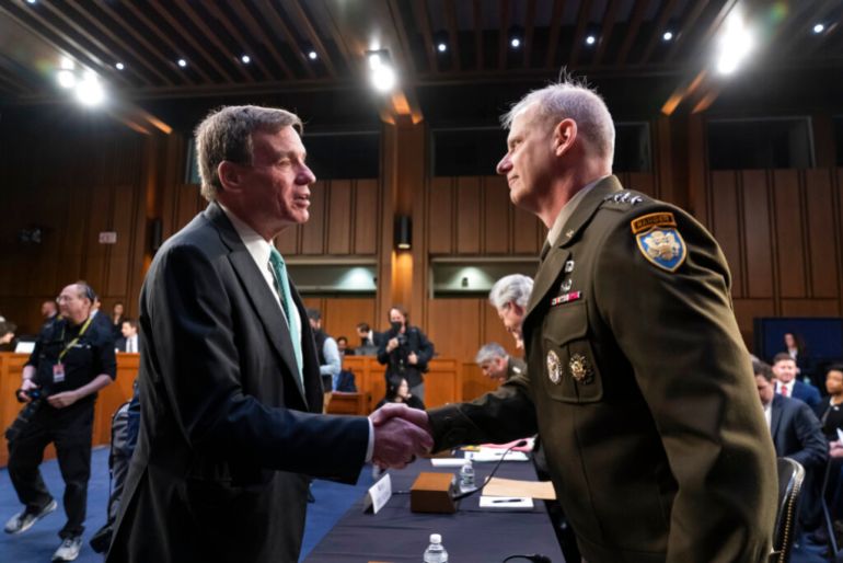 Senate Intelligence Committee Chairman Mark Warner, D-Va., left, greets Defense Intelligence Agency Director Lt. Gen. Scott Berrier, right, shake hands at the start of a hearing on worldwide threats as Russia continues to attack Ukraine.