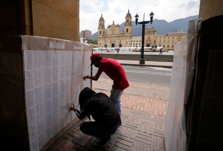 People look at a list of election workers in downtown Bogota, Colombia