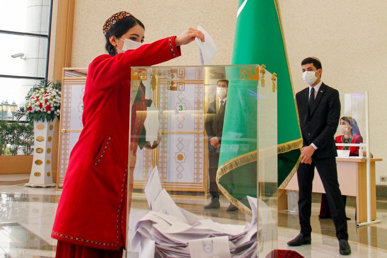 A woman dressed in Turkmen national dress casts her ballot at a polling station
